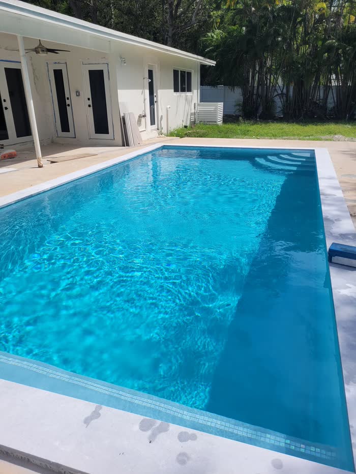 Una piscina turquesa y brillante junto a una casa blanca
